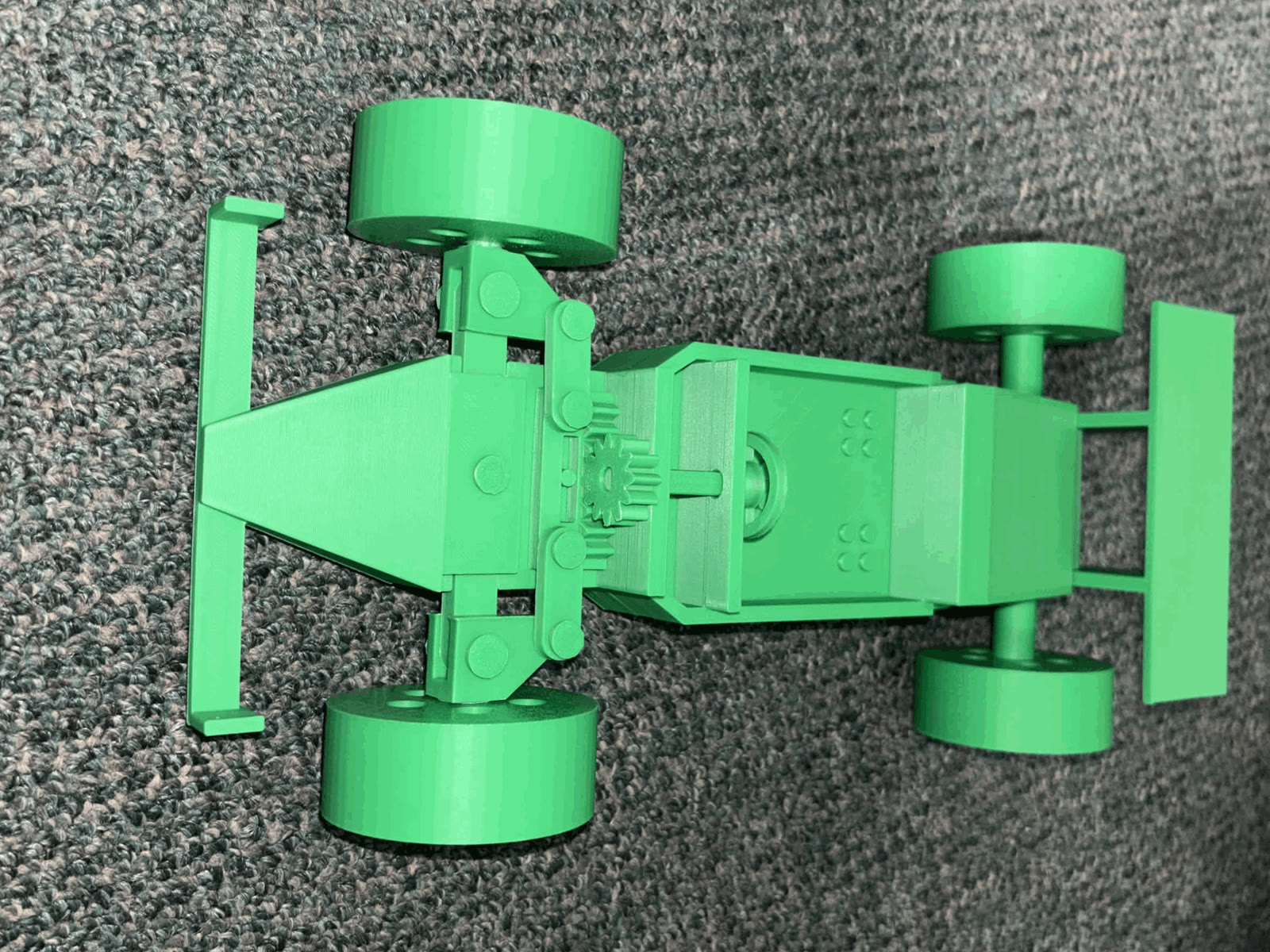 Assembled green PLA racecar seen from above, front wing on the left
