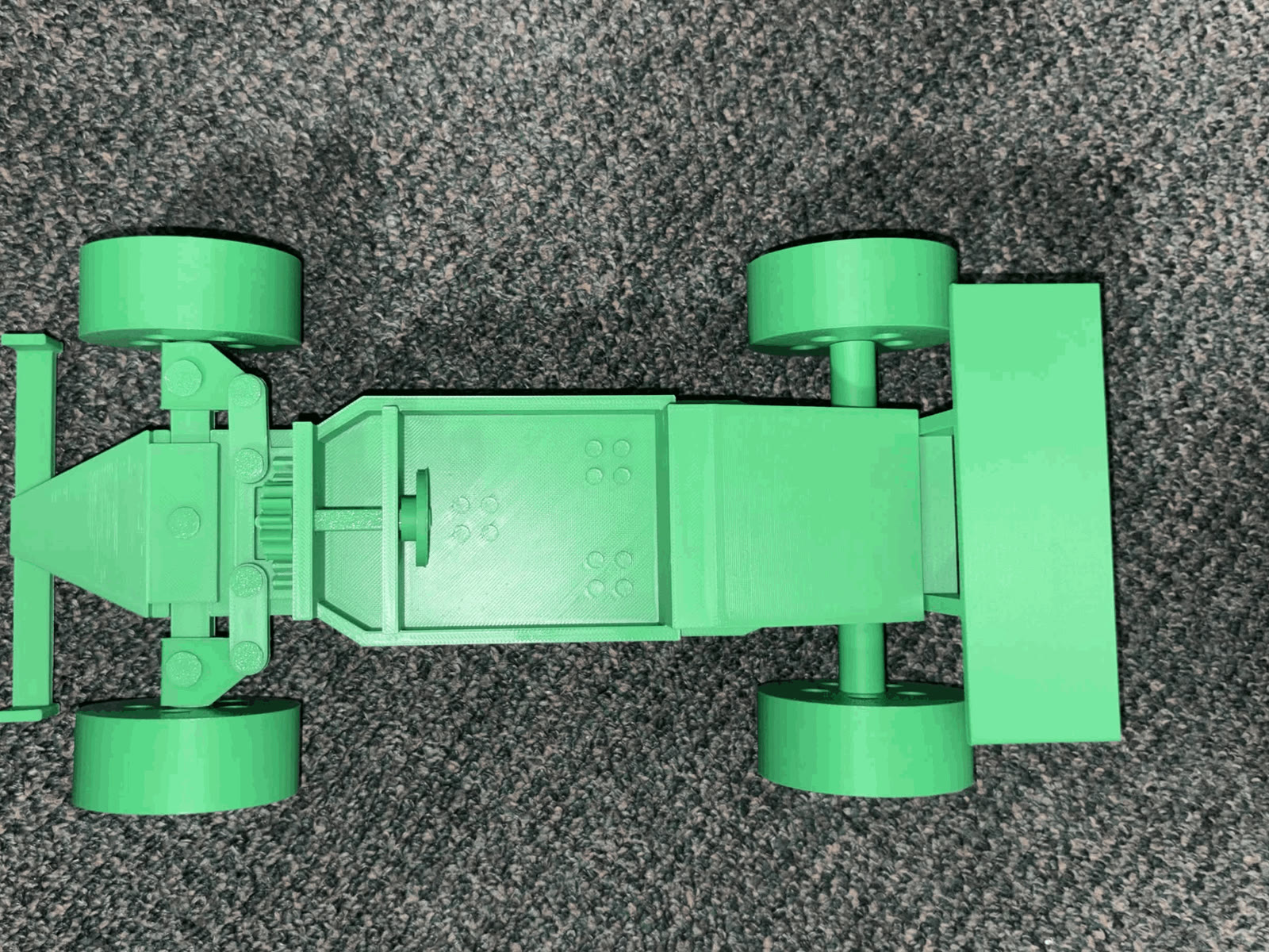 Underside of the green PLA racecar showing the rack, pinion and steering links